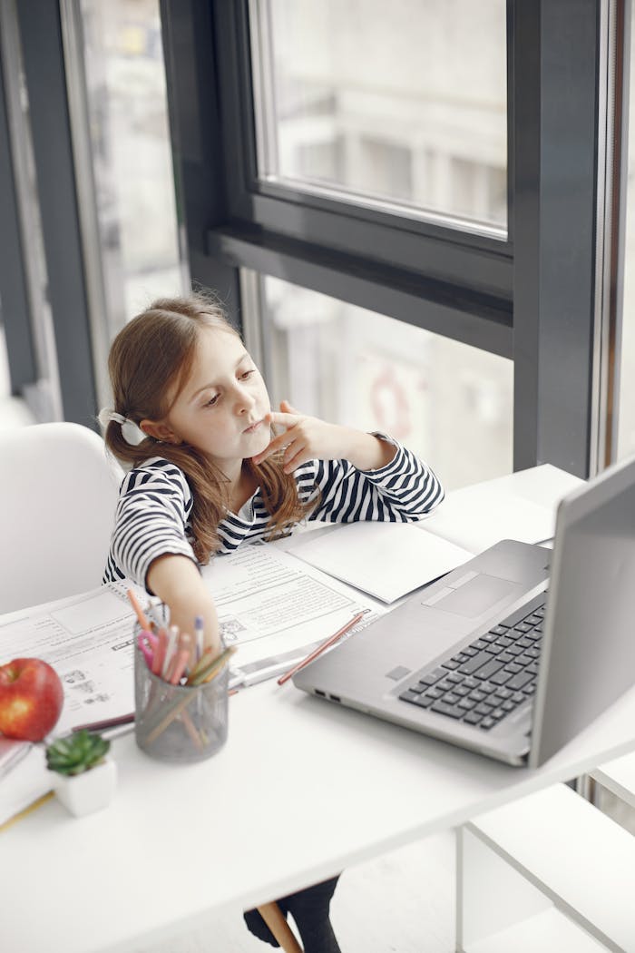services-01 A young girl engaging in online learning at home using a laptop, emphasizing modern education.