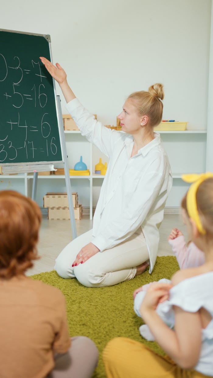 services-03 Teacher instructing children with math problems on chalkboard in classroom.
