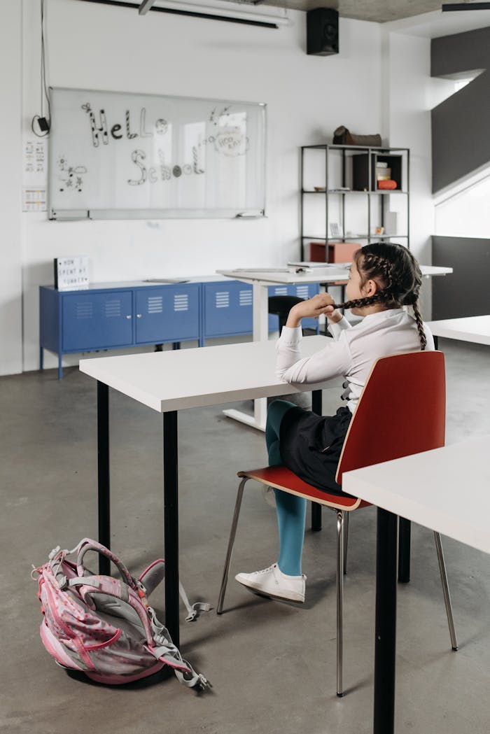 services-03 Girl sitting in classroom facing whiteboard with 'Hello School' on it.